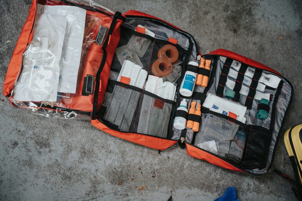 An open red medical bag filled with various supplies on a grey surface