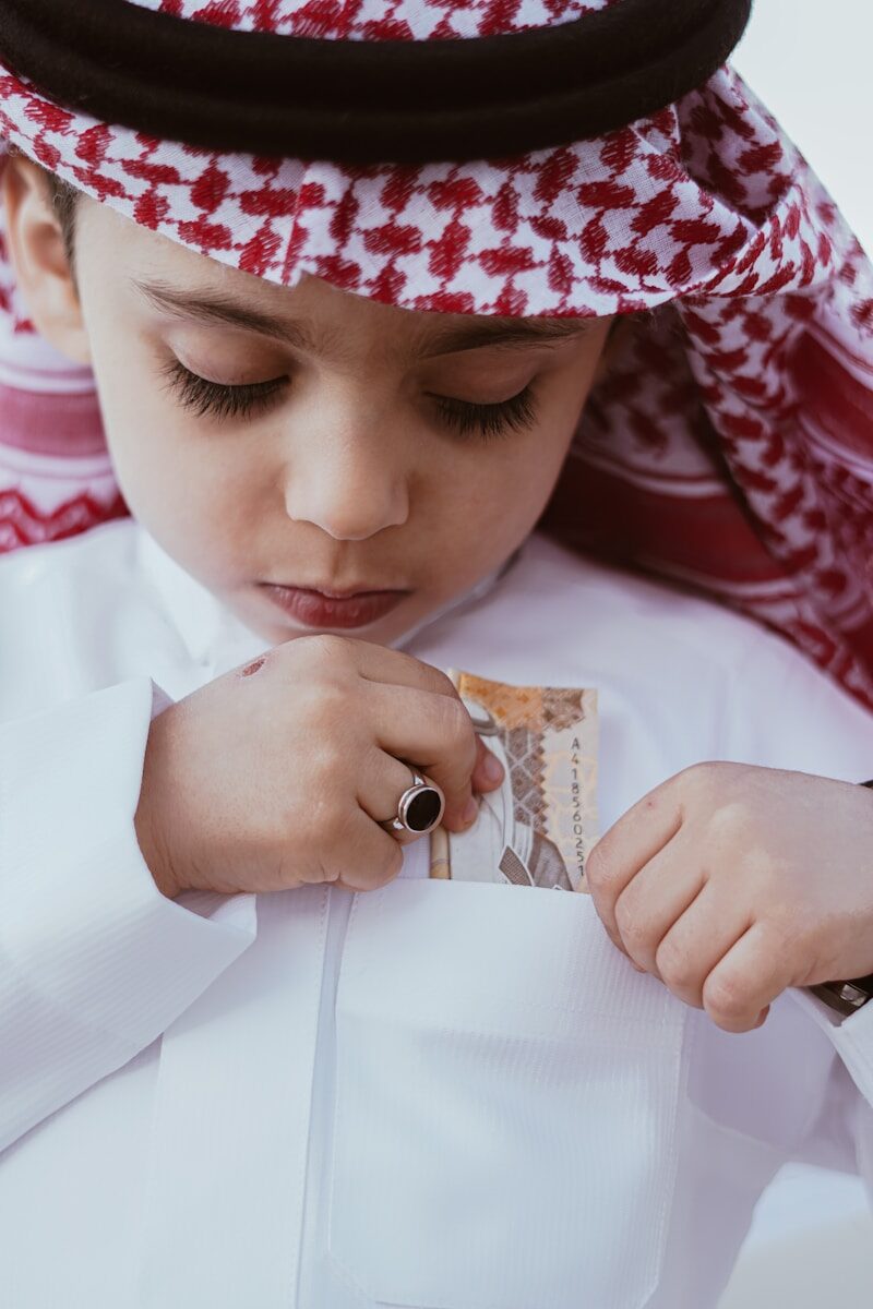 a young boy wearing a white shirt and a red and white hat