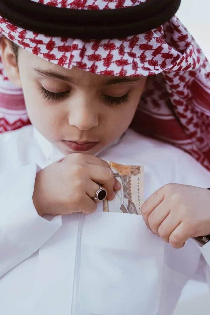 a young boy wearing a white shirt and a red and white hat