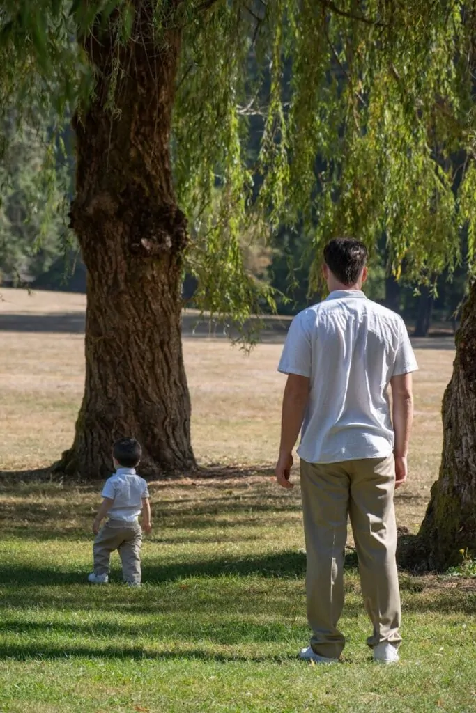 60 Meaningful Things to Do With Your Parents for Every Season and Situation 2 Man and child stand in a grassy park.