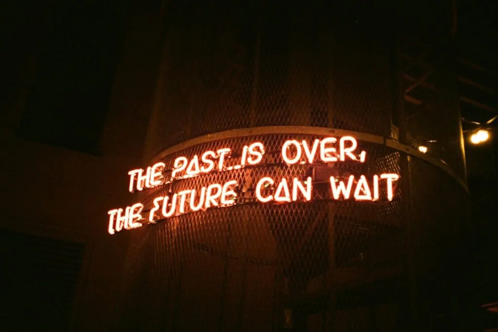 a neon sign that reads the past is over, the future can wait