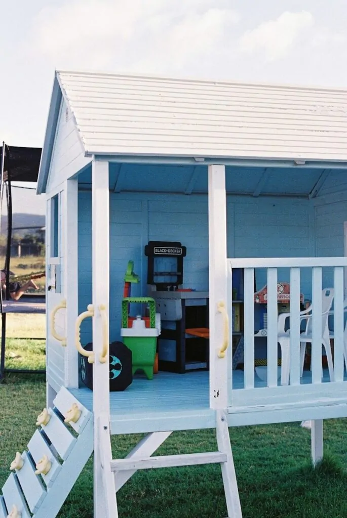 A light blue playhouse with toy kitchen and grill.