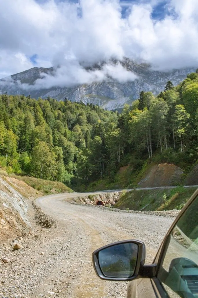 60 Meaningful Things to Do With Your Parents for Every Season and Situation 30 Winding dirt road through lush green mountains under clouds.