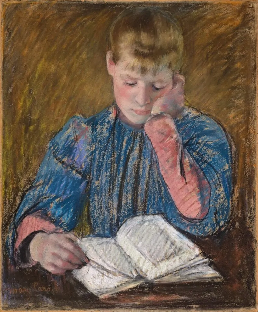 A young person in blue reads a book.