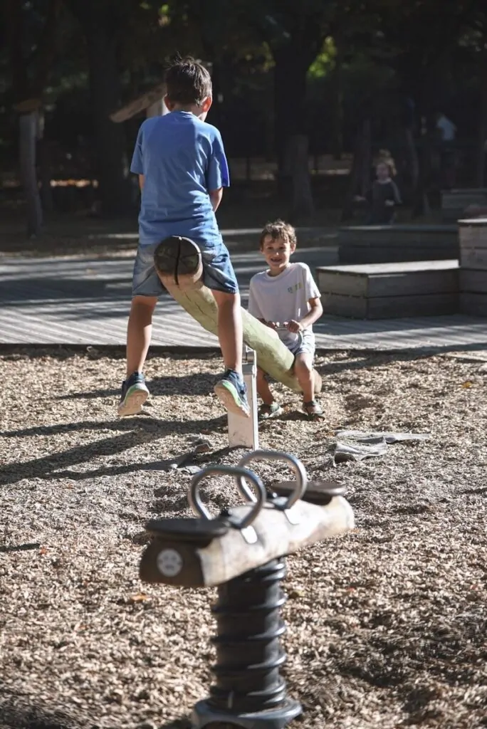 Two boys playing on a seesaw at a playground.