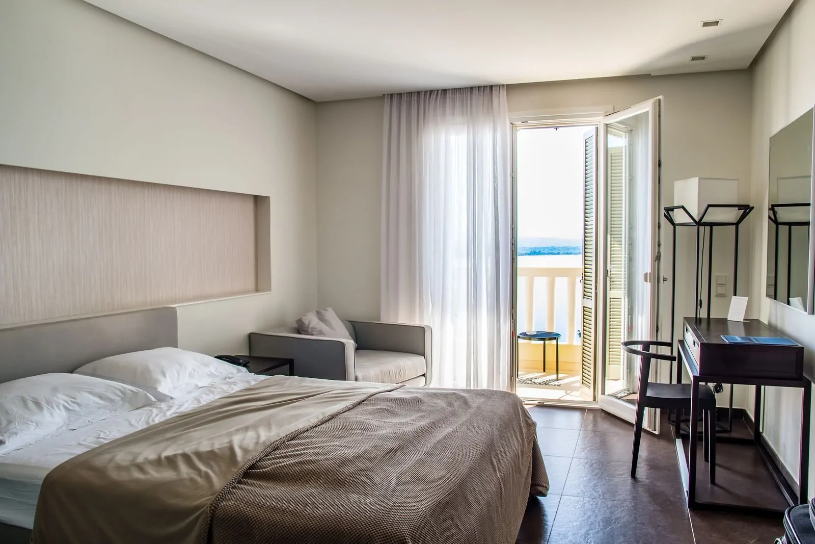 35+ Room Decor Ideas for Small Spaces That Feel Bigger 28 Spacious, elegantly furnished hotel room featuring a balcony with a sea view and modern amenities.