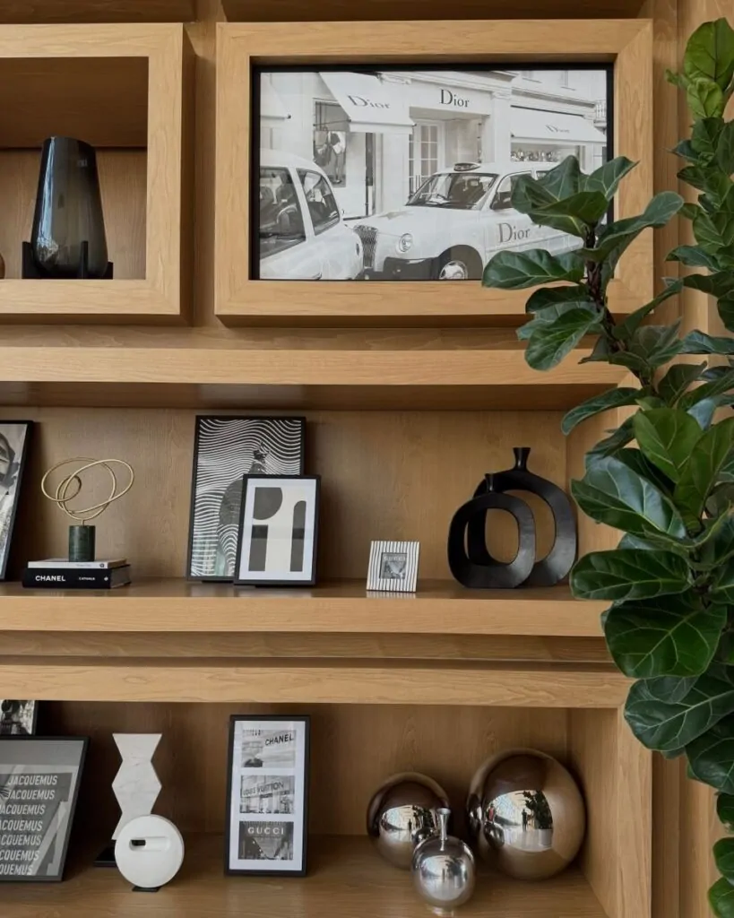 Elegant wooden bookshelf with artistic decor and greenery accent.