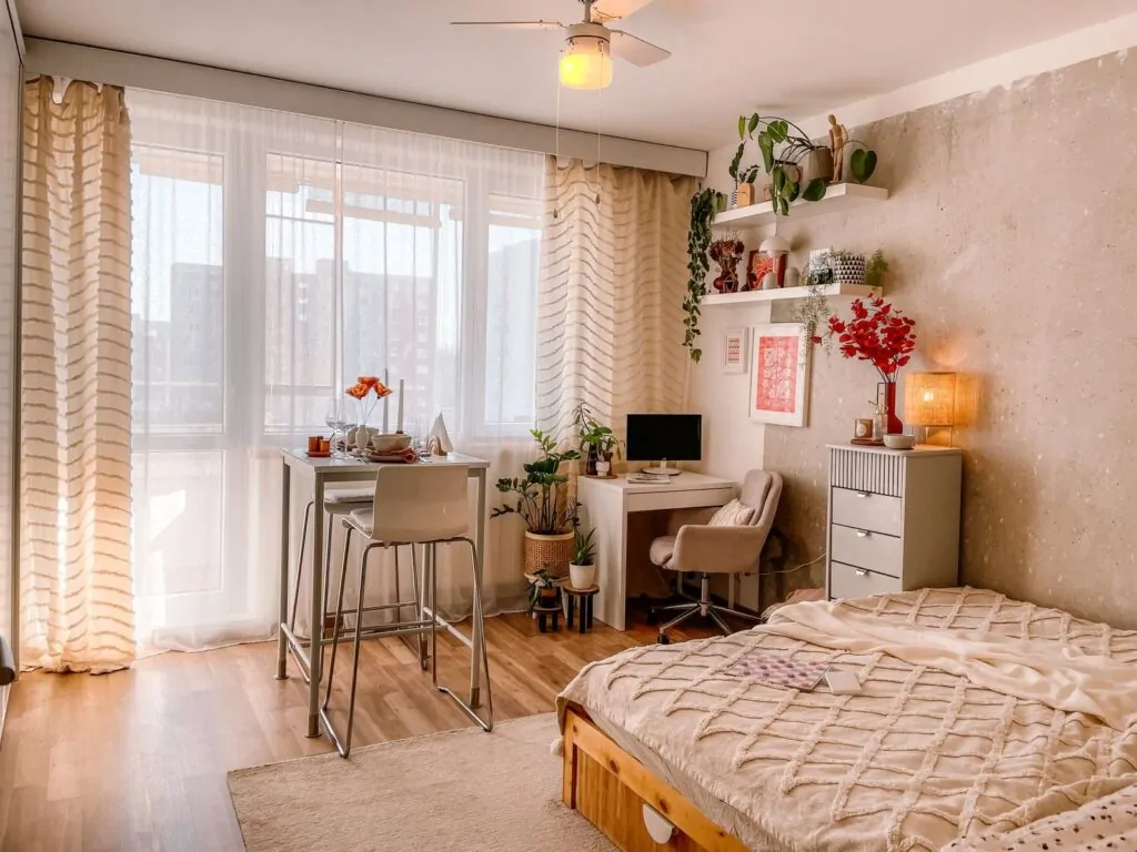 35+ Room Decor Ideas for Small Spaces That Feel Bigger 17 A bright and cozy Scandinavian-style bedroom with wooden floors, plants, and modern furnishings.
