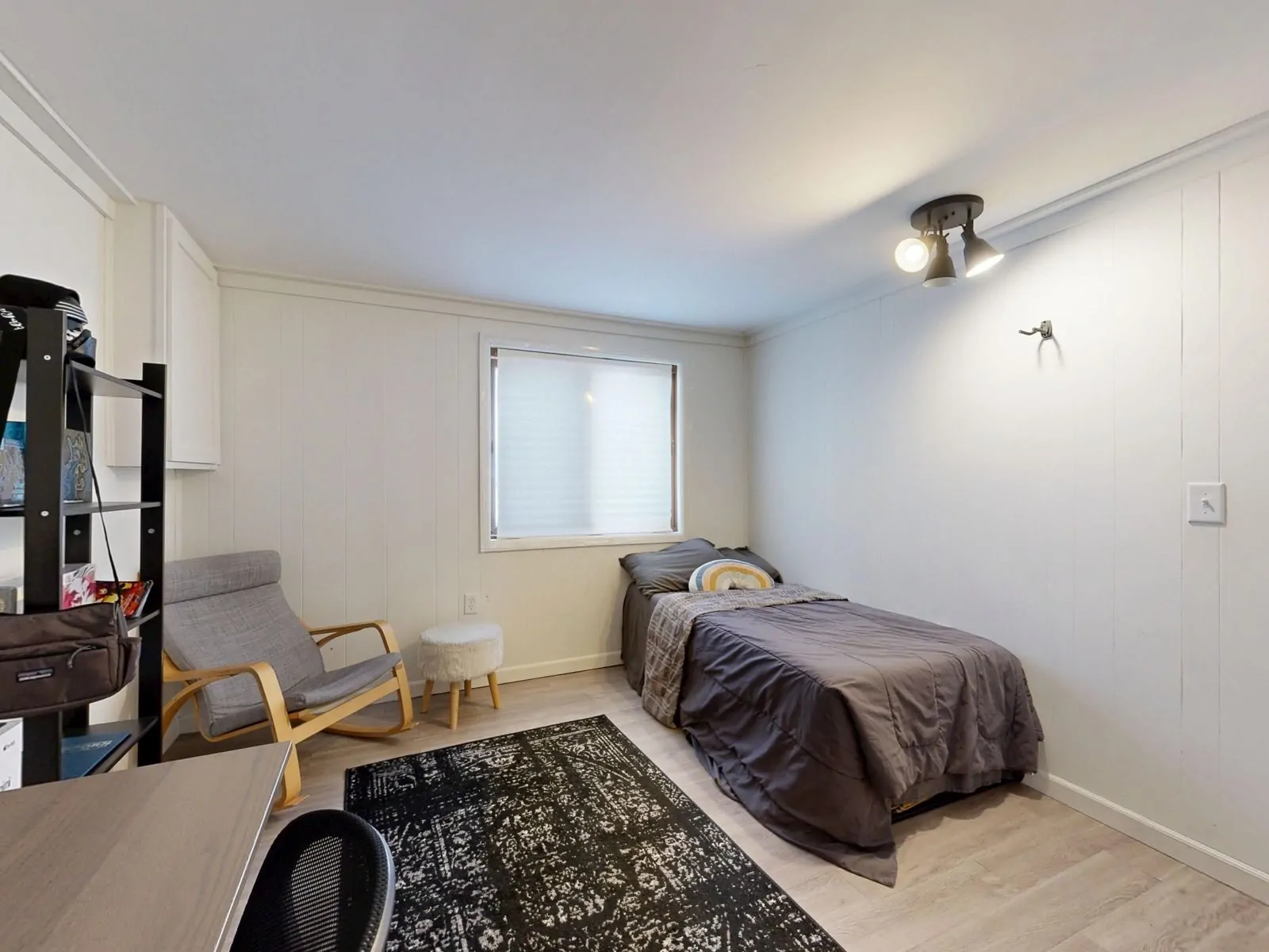 35+ Room Decor Ideas for Small Spaces That Feel Bigger 12 A simple minimalist bedroom with a grey bedspread, armchair, and modern decor.