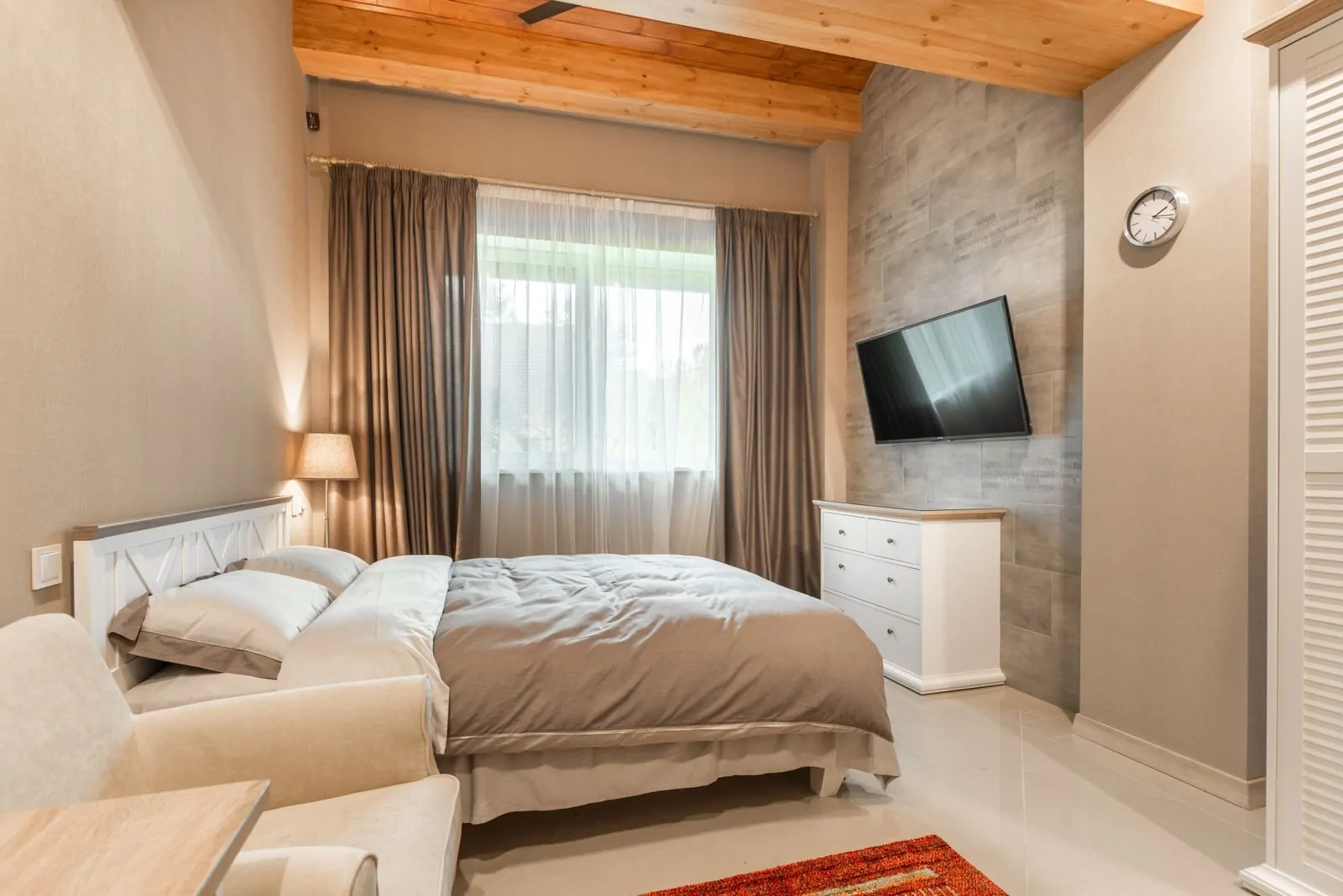 35+ Room Decor Ideas for Small Spaces That Feel Bigger 32 Interior of modern hotel room with comfortable bed near window with curtains and white sofa against tv and dresser