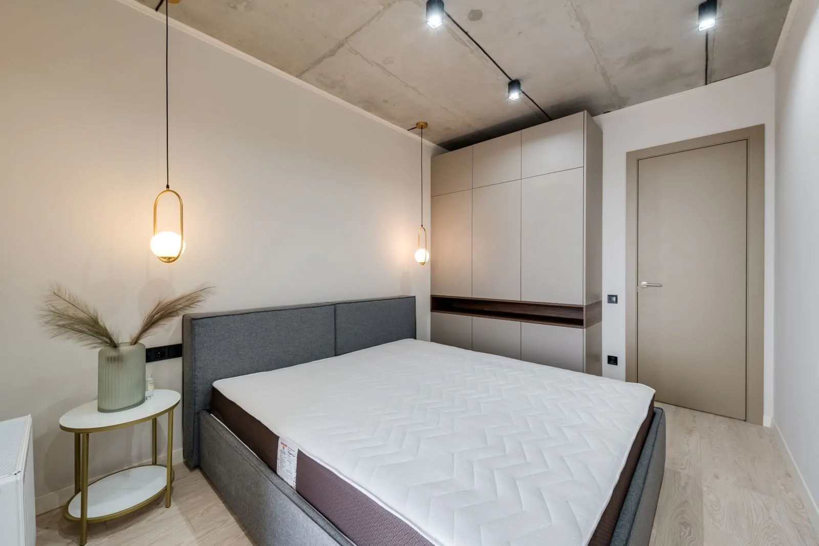 35+ Room Decor Ideas for Small Spaces That Feel Bigger 15 A minimalist bedroom featuring a gray bed, warm lighting, and sleek storage solutions.