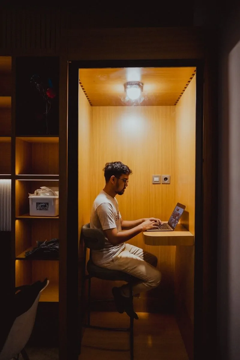 35+ Small Office Ideas for Working From Home 27 Man is working on his laptop in a cubicle.