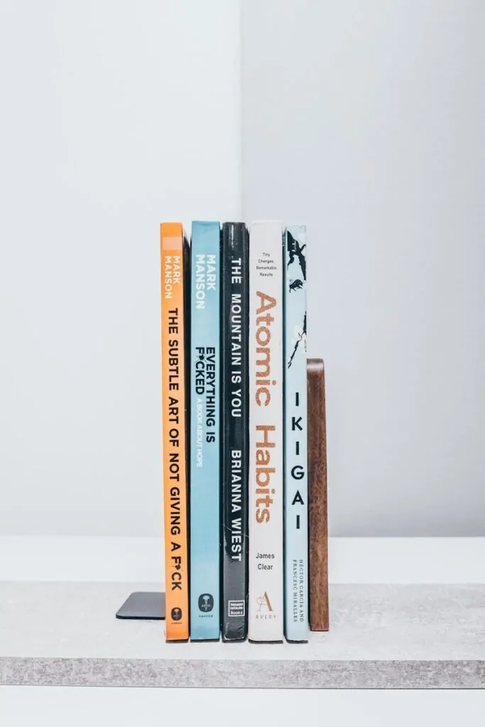 A row of books sitting on top of a white shelf