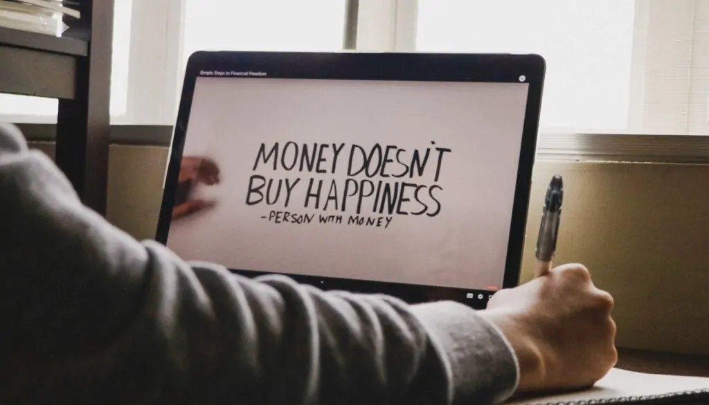 Can Money Buy Happiness? Here’s What Research Says 1 a person writing on a computer screen with a pen