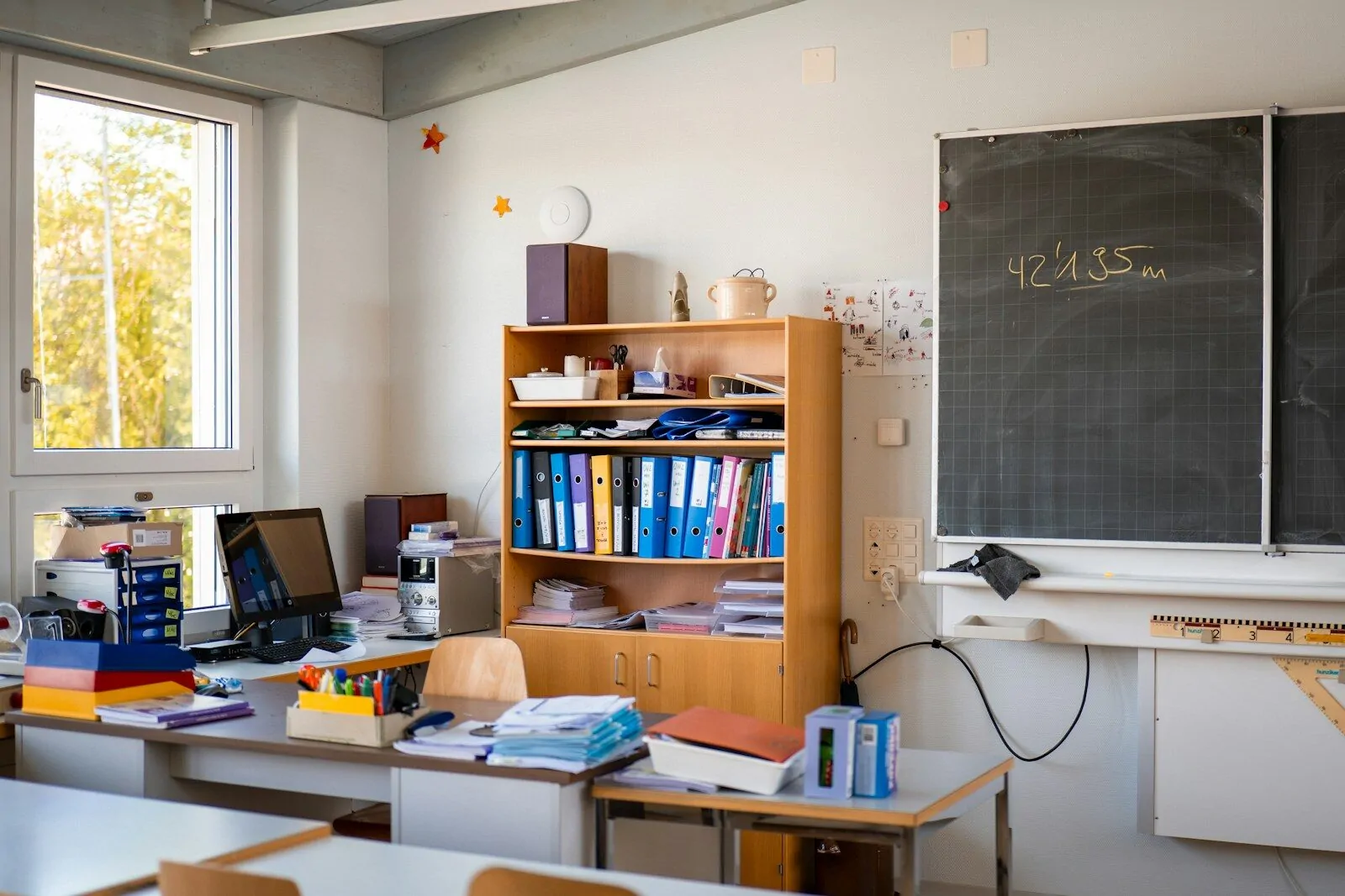 A classroom with supplies, desk, and a chalkboard