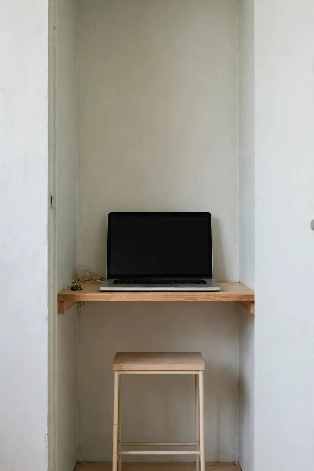 16 Cloffice Ideas Small Spaces Will Love 4 A tiny two-foot-wide closet office with a laptop on a narrow desk board and a slim stool tucked underneath