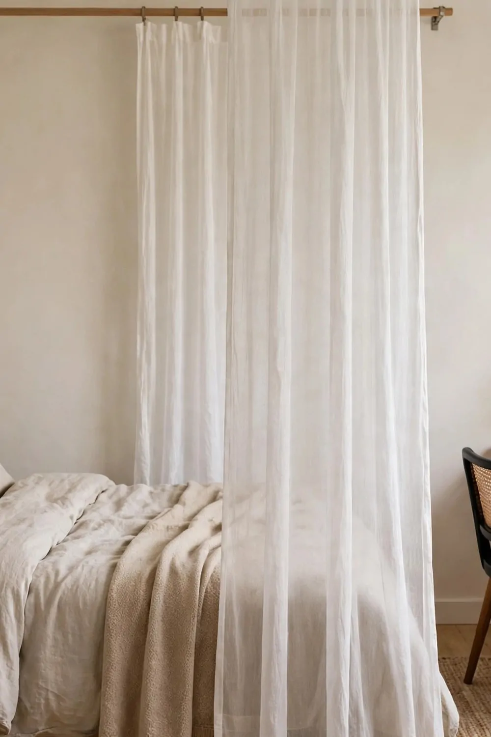 A narrow console table behind a bed headboard holding a laptop and a small lamp