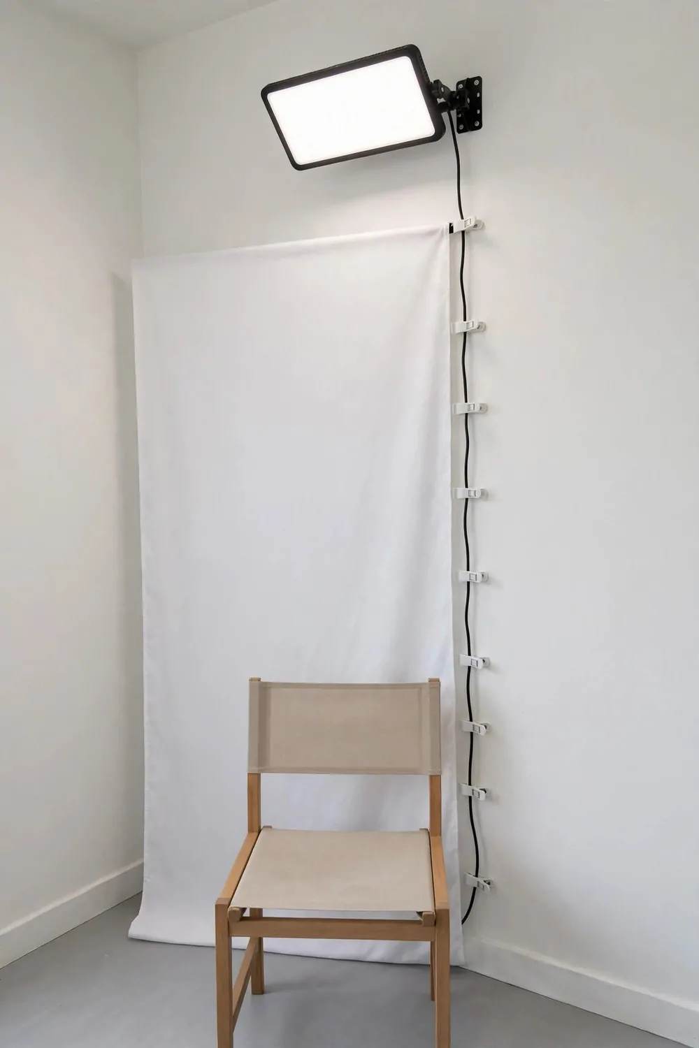 19 Small Photo Studio Setups That Still Look Professional 14 A small LED panel light mounted high on a wall above a chair in a small photo studio