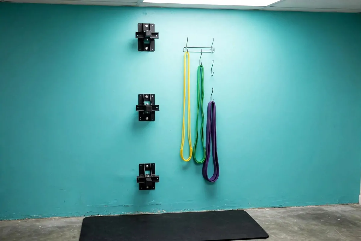 21 Mini Gym at Home Ideas Basement Layouts That Use Dead Space 16 Wall-mounted resistance band anchors at three heights with bands on hooks.