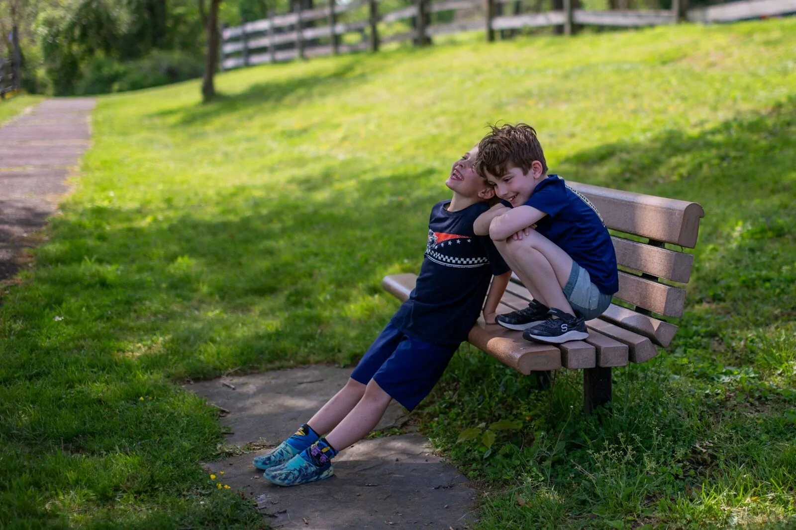 Two boys hugging on a park bench