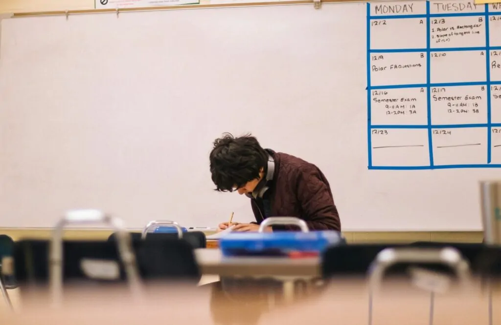 9 Ways to Organize My Life as a Busy Student 1 A student writing on paper at a desk in a classroom