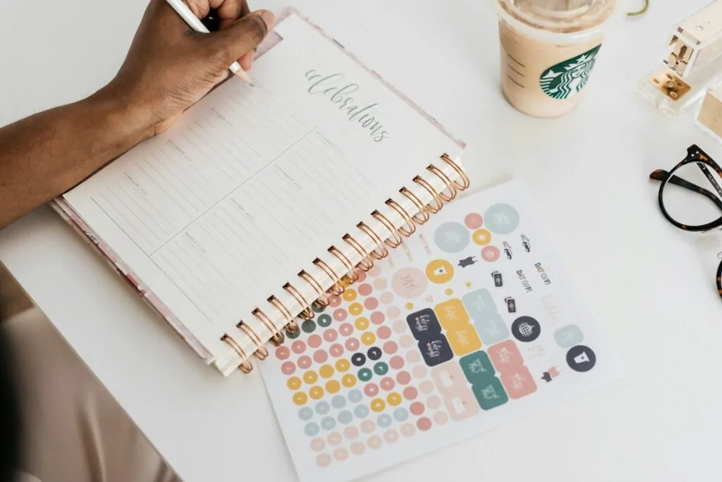 Planner vs Notebook: Which Is Better for Organizing Life? 1 person writing at the tale