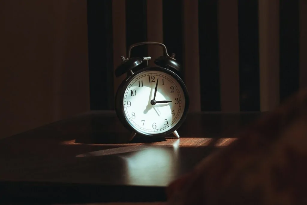 An alarm clock on a wooden table at night