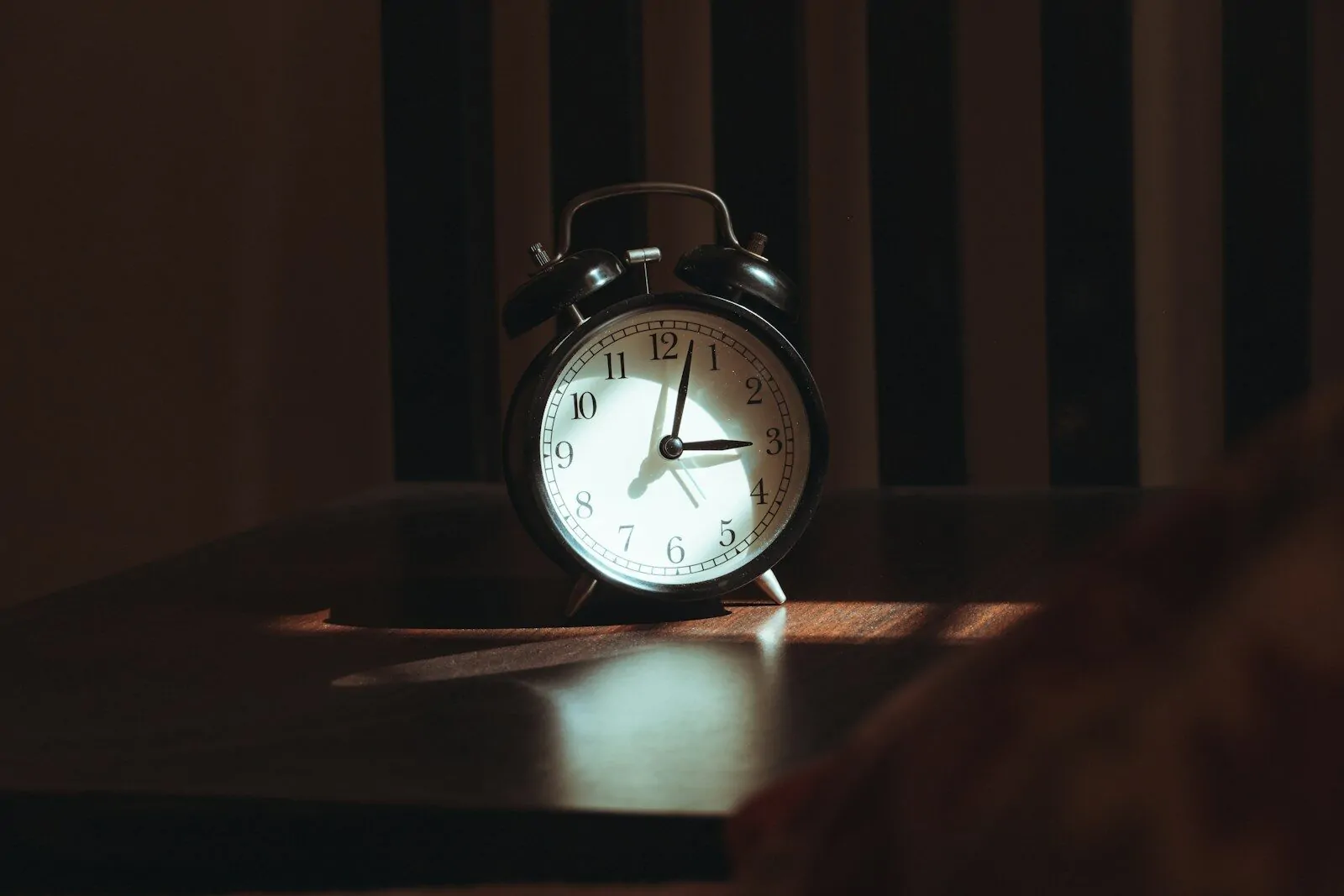 An alarm clock on a wooden table at night