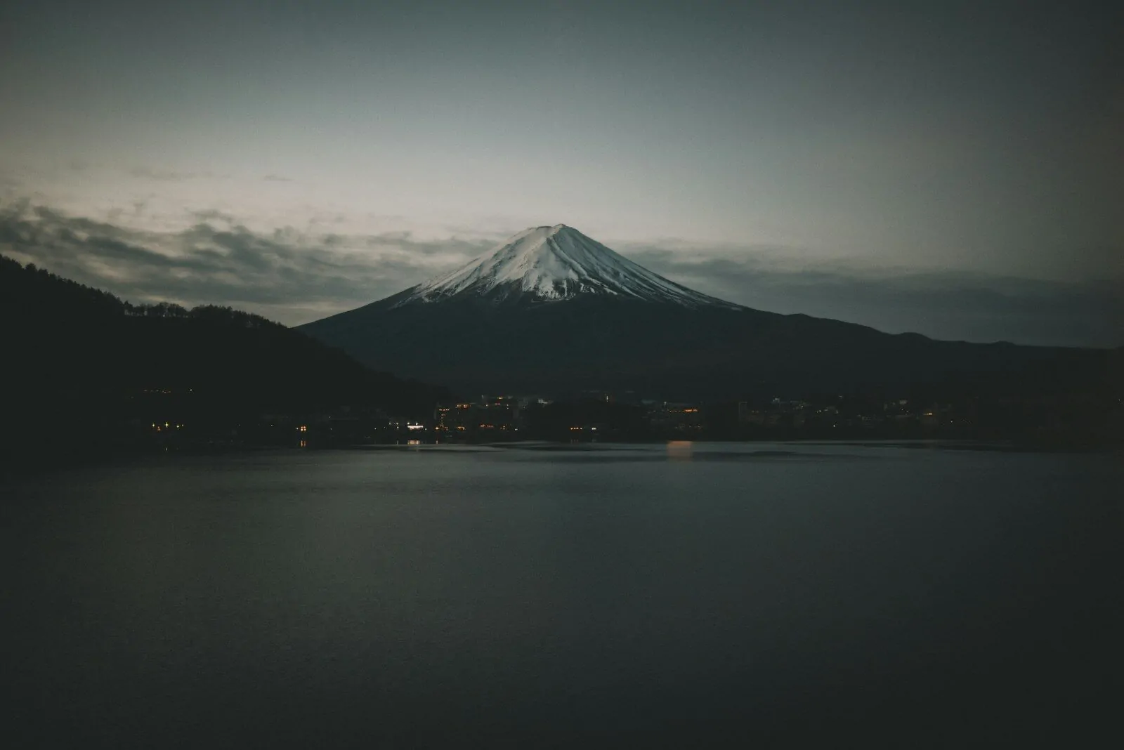 Mount Fuji rising above a dark lake at night in Fujinomiya, Japan