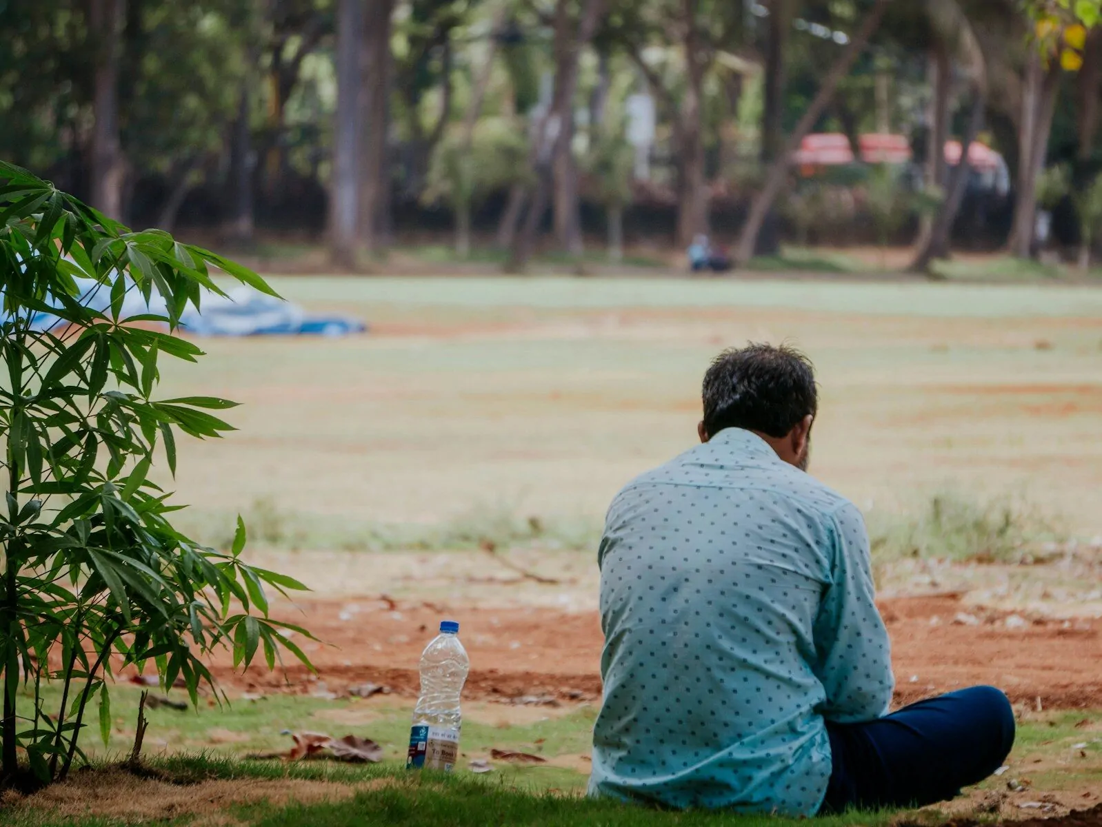 Man sitting on grass with water bottle in a park