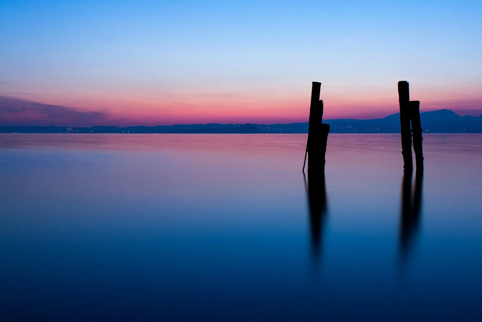 two wooden posts sticking out of the water at sunset